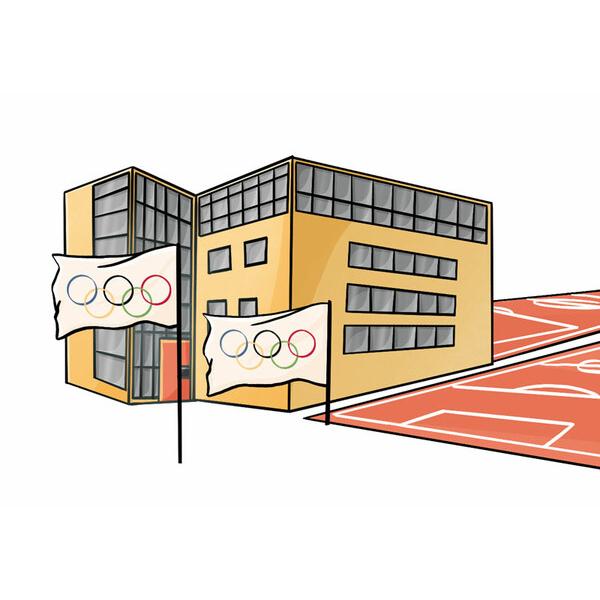 Moderner Gebäudekomplex mit großen Fenstern und zwei Flaggen mit Olympischen Ringen, im Vordergrund ein Sportplatz.